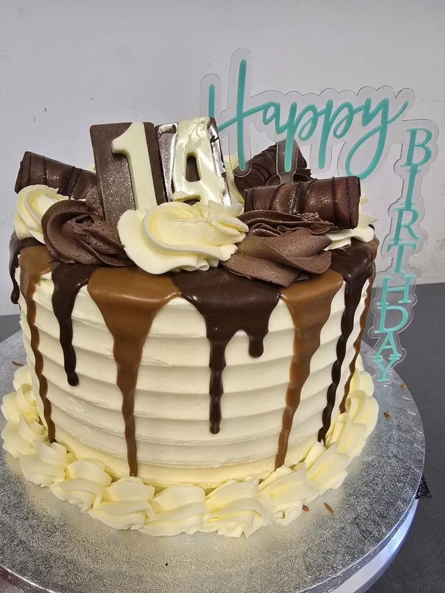 A layered birthday cake with chocolate and caramel drips, topped with “14,” chocolate decorations, and a “Happy Birthday” topper.